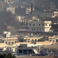Smoke rises in the badly damaged Syrian town of Kobani during heavy fighting between Islamic State and Kurdish peshmerga forces, seen from near the Mursitpinar border crossing on the Turkish-Syrian border, in the southeastern town of Suruc on Monday. | REUTERS