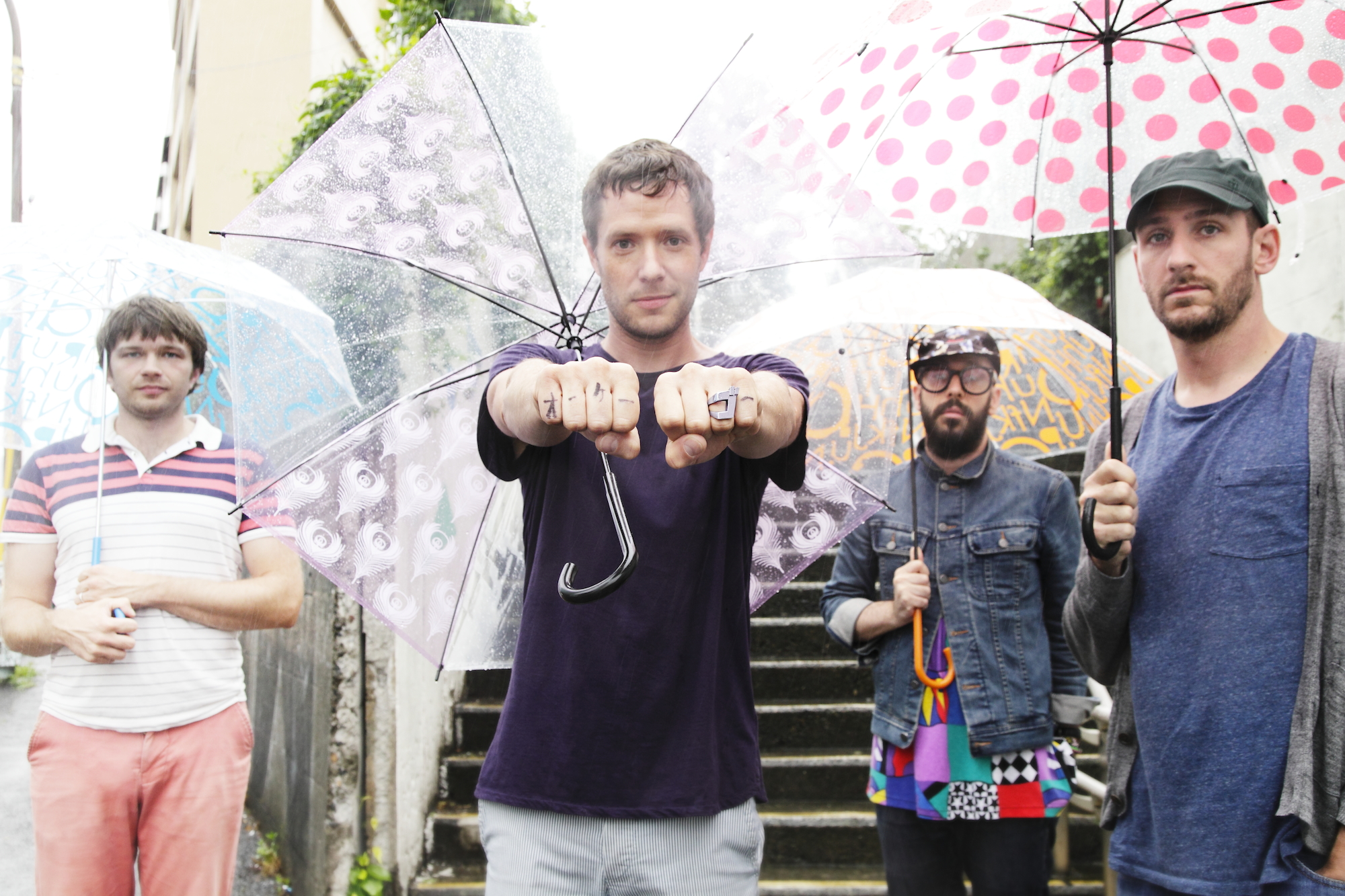 OK Go — (from left) Andy Ross, Damian Kulash, Tim Northwind and Dan Konopka  — demonstrate their prowess with open umbrellas in Shibuya. | CHIEKO KATO