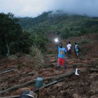 A man shines a light as dusk falls at the site of a mudslide at the Koslanda tea plantation in Badulla district, about 220 km (140 miles) east of Colombo, Wednesday. The mudslide triggered by monsoon rains buried scores of workers’ houses at the tea plantation, killing at least 10 people and leaving more than 250 missing, an official said. Hundreds feared buried under Sri Lanka mudslide