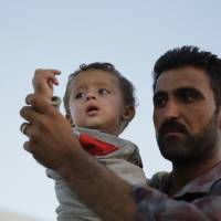 As fighting intensified between Syrian Kurds and Islamic State militants on Sunday, Kurdish refugees board a truck near Suruc, Turkey, following their arrival from the Syrian border town of Kobani. | AP