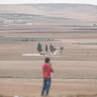 Turkish Kurds watch the unfolding conflict in the Syrian town of Kobani from the Mursitpinar border crossing in the town of Suruc, southeast Turkey, on Sunday. | AP
