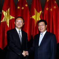 Chinese State Councilor Yang Jiechi (left) shakes hands with Vietnamese Deputy Prime Minister and Minister of Foreign Affairs Pham Binh Minh in Hanoi on Monday. | AFP-JIJI