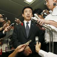 Health minister Yasuhisa Shiozaki responds to reporters\' questions Monday night after a man arriving at Haneda airport in Tokyo was hospitalized and undergoing a test for Ebola. | KYODO