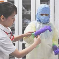 Nagasaki University Hospital nurses on Wednesday practice donning the kind of protection needed for Ebola. | KYODO