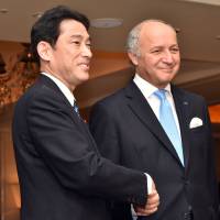French Foreign Minister Laurent Fabius is welcomed by Foreign Minister Fumio Kishida prior to a working dinner in Tokyo on Sunday. | AFP-JIJI