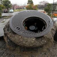 Manholes in Urayasu, Chiba Prefecture, stand well above the surface of the ground as a result of the liquefaction of the surrounding soil caused by the Great East Japan Earthquake on March 11, 2011. | BLOOMBERG