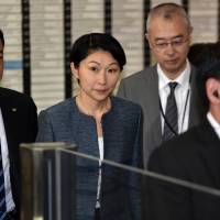 Trade and industry minister Yuko Obuchi (second from left) leaves her office in Tokyo on Saturday. On Monday she is expected to hand Prime Minister Shinzo Abe a letter of resignation concerning the alleged misuse of political funds. | AFP-JIJI