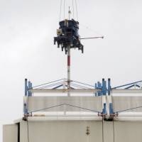 A device to punch holes in the cover over the reactor 1 building at the Fukushima No. 1 nuclear plant is moved into position on Wednesday. | KYODO