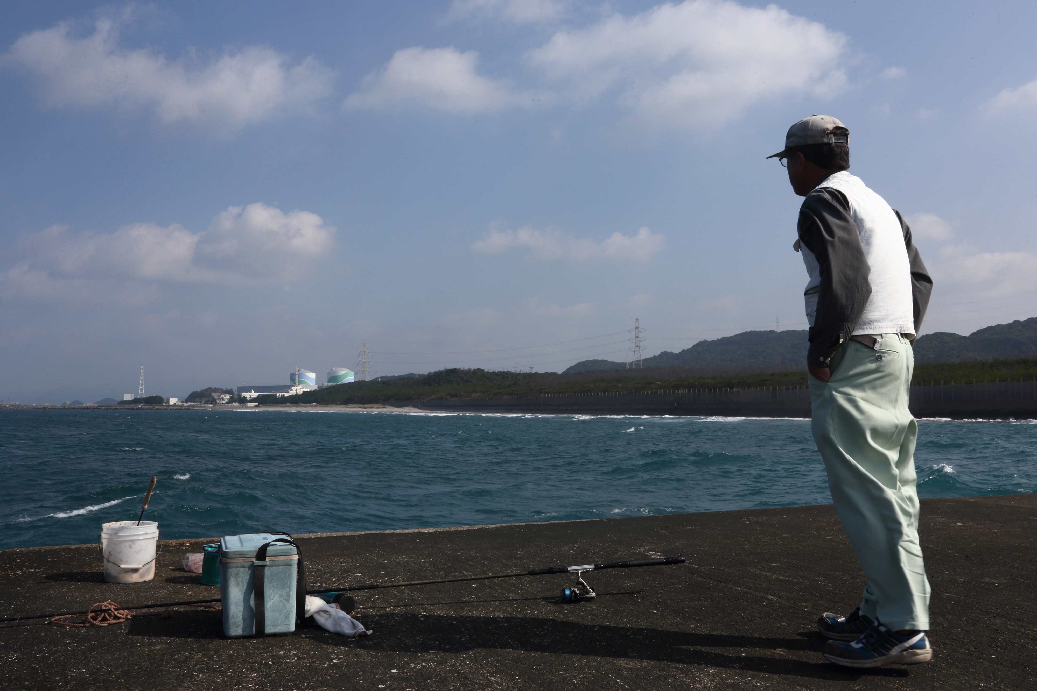 A fisherman gazes at the two reactors of Kyushu Electric Power Co.'s Sendai nuclear plant in Satsumasendai, Kagoshima Prefecture, on Monday. | BLOOMBERG