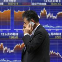 Money down: Two men walk past an electronic board showing Japan\'s Nikkei average outside a brokerage in Tokyo last month. The weakness of the yen contributed to more risk-taking by investors, which boosted shares, but the currency\'s drop hasn\'t been all good news. | REUTERS