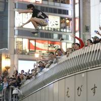 A Hanshin Tigers fan jumps from the Ebisubashi Bridge into the Dotonbori River in Osaka\'s Minami district on Saturday night after the baseball team defeated the Yomiuri Giants to win the Central League Climax Series Final Stage and advance to the Japan Series, setting off wild celebrations. | KYODO