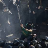 A far-right nationalist protester clashes with law enforcement members on the Day of Ukrainian Cossacks, which honors the Cossacks\' role in the creation of a democratic Ukraine without sharp class divisions, during a rally near the parliament building in Kiev on Tuesday. The protesters demanded the release of political prisoners in Ukraine. | REUTERS