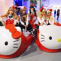 Fans dressed as Hello Kitty sit on huge Kitty-themed slippers at a special event in Los Angeles on Wednesday. | KYODO