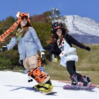 Snowboarders make the most of the last days of autumn at the foot of Mount Fuji on Friday. The volcano saw its first snow of the winter dust its upper slopes on Thursday morning. | KYODO
