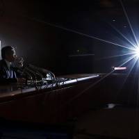 Bank of Japan Gov. Haruhiko Kuroda sips a glass of water as he sits next to a placard showing BOJ policy decisions during an Oct. 31 news conference at the central bank\'s Tokyo headquarters. | REUTERS