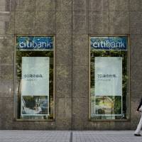 A pedestrian walks past a Citigroup Inc. Citibank branch in Tokyo in August. | BLOOMBERG