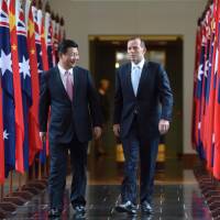 Chinese President Xi Jinping and Australian Prime Minister Tony Abbott walk together as they leave the House of Representatives at Parliament House in Canberra on Monday. | AFP-JIJI