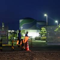 Guards are stationed at the entrance to Kyushu Electric Power Co.\'s Sendai nuclear plant in Satsumasendai, Kagoshima Prefecture, on Oct. 26. | BLOOMBERG