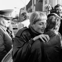 An East Berlin citizen (facing camera) embraces a West Berlin woman while an East German border soldier watches at the Invalidenstrasse border checkpoint after the opening of the East German border was announced in Berlin on Nov. 10, 1989. | REUTERS