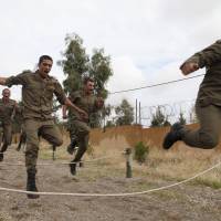 Kurdish peshmerga fighters run over obstacles as part of their training at their camp in Irbil, Iraq, on Nov. 3. | REUTERS