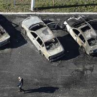 A man walks past a row of charred cars Tuesday at a dealership in Dellwood, Missouri, after they were burned in overnight protests following a grand jury\'s decision not to indict a white police officer in the killing of an unarmed black 18-year-old. | AP