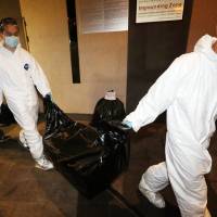 The remains of a woman are removed from an apartment in Hong Kong after the grisly discovery of two female corpses, including one in a suitcase in the Wanchai district on Saturday night. Hong Kong police on Sunday arrested a 29-year-old British man who works as a trader for Bank of America Merrill Lynch over the double murder. | AFP-JIJI