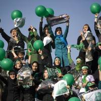 Female supporters of former Iranian Prime Minister Mir Hossein Mousavi wave posters and green balloons in Tehran during 2009\'s so-called Green Revolution. The funeral on Sunday for pop idol Morteza Pashaie saw some of the biggest public gatherings since the 2009 unrest. | BLOOMBERG