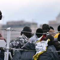 Migrants wait to disembark from the coast guard boat Fiorillo in the Sicilian port of Palermo on Oct. 20. | AFP-JIJI