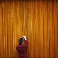 An attendant puts clamps on a curtain inside the Great Hall of the People during the closing ceremony of the Chinese People\'s Political Consultative Conference in Beijing in March 2014. | REUTERS