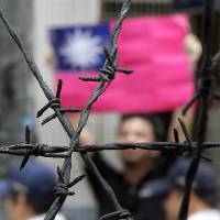 A pro-democracy activist holds up Taiwan\'s flag in front of police officers during a visit by the director of China\'s Taiwan Affairs Office, Zhang Zhijun, to the labor activity center in New Taipei City on June 26. | REUTERS