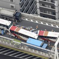 Tour buses involved in an accident are seen on a section of the Metropolitan Expressway in Itabashi Ward, Tokyo, on Saturday morning. Forty-six people, including elementary school children, sustained minor injuries in the accident triggered by a motorcycle changing lanes. | KYODO