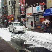 A street in Naka Ward, Nagoya, is covered in white foam after a fire extinguishing system was accidentally triggered in a parking facility Sunday afternoon. | KYODO