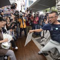 Park Geun-hye tries to lay flowers at a statue of Chun Tae-il in Seoul in August 2012, as a labor rights activist blocks the way. Chun killed himself in 1970 in protest of labor conditions, an act seen as an expression of dissent against the rule of Park Chung-hee, Geun-hye\'s father. | AP