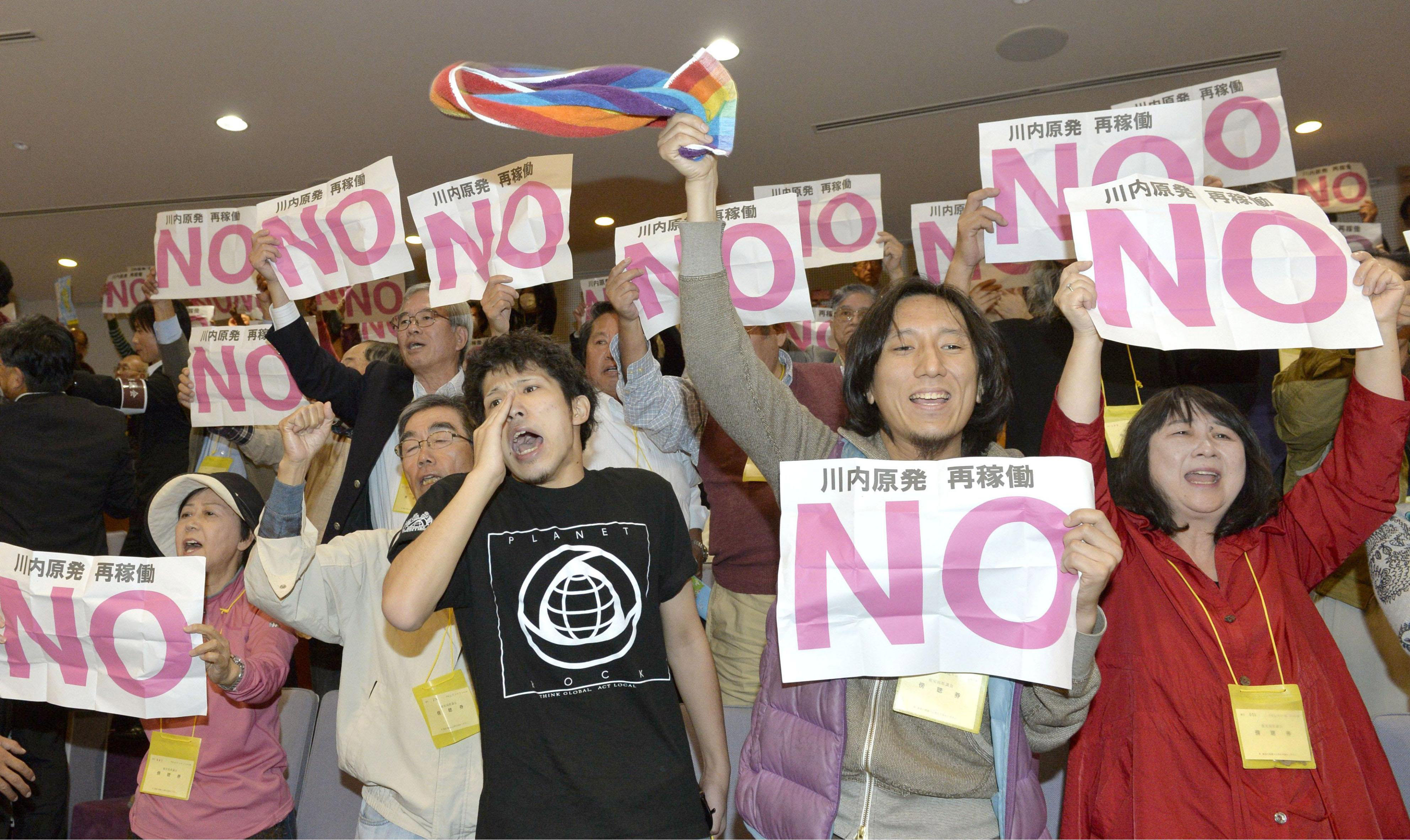 People standing in the public gallery of the Kagoshima Prefectural Assembly on Friday protest its decision to approve the restart of two reactors at the Sendai nuclear power plant. Gov. Yuichiro Ito approved the restart later the same day. | KYODO