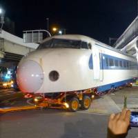 An old 0 series Shinkansen train unit is pulled out by a truck from the Modern Transportation Museum in Osaka early Friday morning. | KYODO