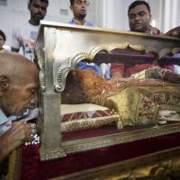 A man prays as he touches a coffin containing relics of St. Francisco Xavier, the Jesuit missionary who exported Christianity to Japan in the 16th century, as the public display of the items began in Old Goa, India, on Saturday. | KYODO