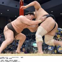 Steady as she goes: Hakuho (left) shoves Aminishiki out of the ring at the Kyushu Grand Sumo Tournament on Monday. | KYODO