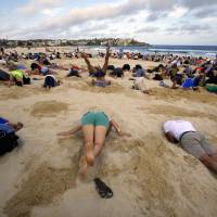 Shore thing: People participate in a protest against Group of 20 nations with poor emissions records by burying their heads in the sand at Sydney’s Bondi Beach on Nov. 13. | REUTERS