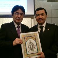Turkmenistan Ambassador Gurbanmammet Elyasov (right) and Kazuyuki Hamada, a member of the House of Councillors show the newly published Japanese version of works by Turkmen poet Magtymguly Pyragy on Nov. 20 in Tokyo. | CHIHO IUCHI