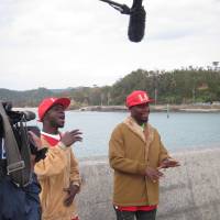 You\'re not alone: Ugandan singers Musa Jian (left) and Baswali Kiramu perform \"Hitori ni Shinaide\" at Teima fishing port in Henoko. | JANE CLOSE