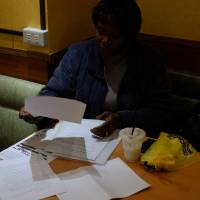 Obueza catches up on paperwork at a cafe. PRAJ recently began printing membership cards for the 590 former detainees it organizes. The cards are meant to serve as an alternate means of identification, and to provide members with immediate access to PRAJ’s network of lawyers and advocates. Obueza visits detention centers daily, and is often the only advocate available to Japanese-illiterate detainees seeking legal and moral support.  | DREUX RICHARD