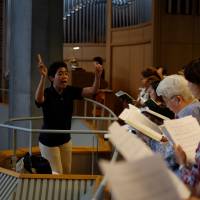 Arlyne Santos, director of the English-language choir at St. Ignatius Church, conducts during Mass in October. Membership in the choir is open to all, regardless of musical ability. Santos acknowledges this can sometimes make her job stressful, but says, “If we can bring them joy and bring them closer to God, it’s OK if I have to put my sanity at stake sometimes.” | DREUX RICHARD
