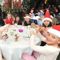 Children from Nishimachi International School in Tokyo show reindeer ornaments they made from recycled corks at the Grand Hyatt Tokyo in Minato Ward on Thursday as part of the hotel\'s Circle of Love charity program to support children in the disaster-hit Tohoku region, as General Manager Steve Dewire (third from left) looks on. | YOSHIAKI MIURA