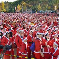 About 11,000 volunteers in Santa Claus costumes pack Osaka Castle Park in Osaka\'s Chuo Ward on Sunday. Using some of the money collected in the form of participation fees, Akaruku Love, a local event organizer, will buy and donate gifts to about 800 hospitalized children suffering from intractable diseases. | KYODO