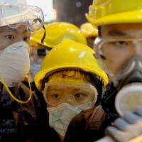 Pro-democracy demonstrators wearing protective gear stare at police officers in the Mong Kok shopping district of Hong Kong before dawn on Wednesday, after protesters\' barricades were dismantled in the area the previous day. | KYODO