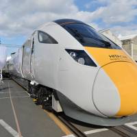 New train cars developed by Hitachi Ltd. for a high-speed railway serving locations including London and Edinburgh are unveiled at the company\'s plant in Kudamatsu, Yamaguchi Prefecture, on Thursday. The train, which is scheduled to begin service in 2017 after test runs, can operate at a maximum speed of 200 kph and is capable of running along segments of track without electric power by using its own diesel-engine generator. | KYODO