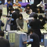 Election staff members open ballot boxes for vote counting in the parliamentary lower house elections at a ballot counting center in Tokyo. | AP