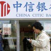 Pedestrians pass in front of a CITIC bank branch in Beijing in April. | REUTERS