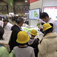 Elementary school students listen as a Fujitsu Ltd. employee discusses their vegetable-growing project on Thursday at the Eco-Product 2014 expo. | SHUSUKE MURAI