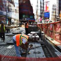 Laborers work on a footpath and road way construction site in Times Square in New York on Oct. 8. 321,000 hired in U.S. last month